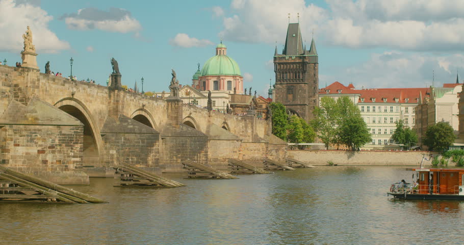 Scenic view of Charles Bridge and old town towers across Vltava River during a sunny summer day