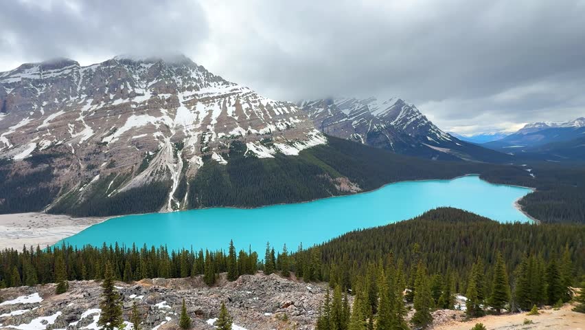 Blue lake surrounded by mountains in Canada. Peyto lake. The sky has clouds. The scene shows nature and vast landscapes.