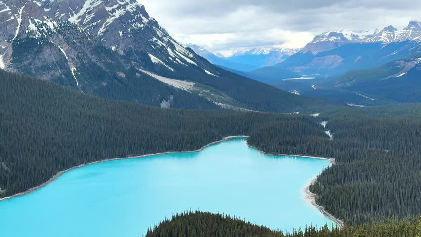 Blue lake surrounded by mountains in Canada. Peyto lake. The sky has clouds. The scene shows nature and vast landscapes.