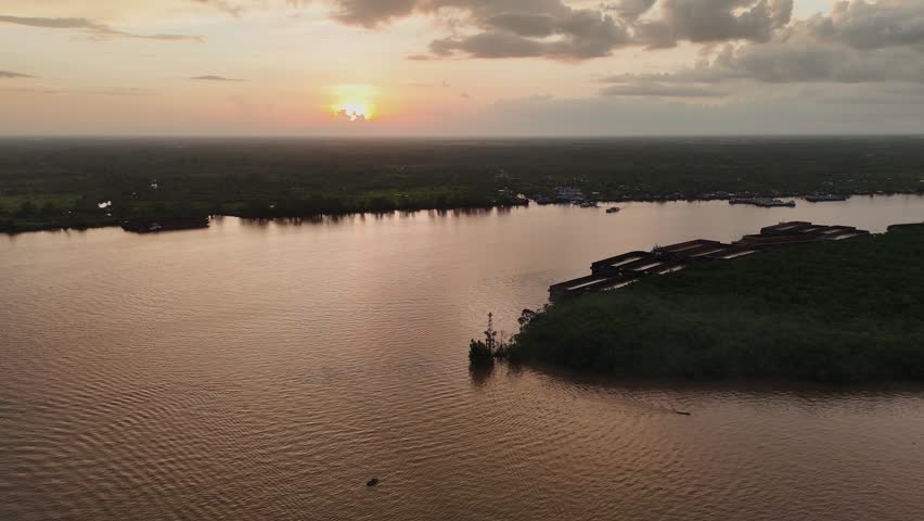 Aerial view of Barito River at sunset with a barge navigating the calm waters in Banjarmasin, South Kalimantan, Indonesia.
