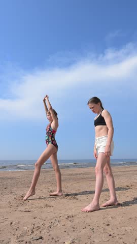 Teenage girls doing handstands on a summer sea sand beach.
