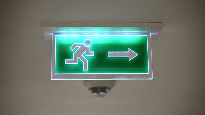 Green emergency exit sign in hotel corridor, building evacuation safety way out, arrow navigation sign fire drill safety procedures concept and fire protection concept