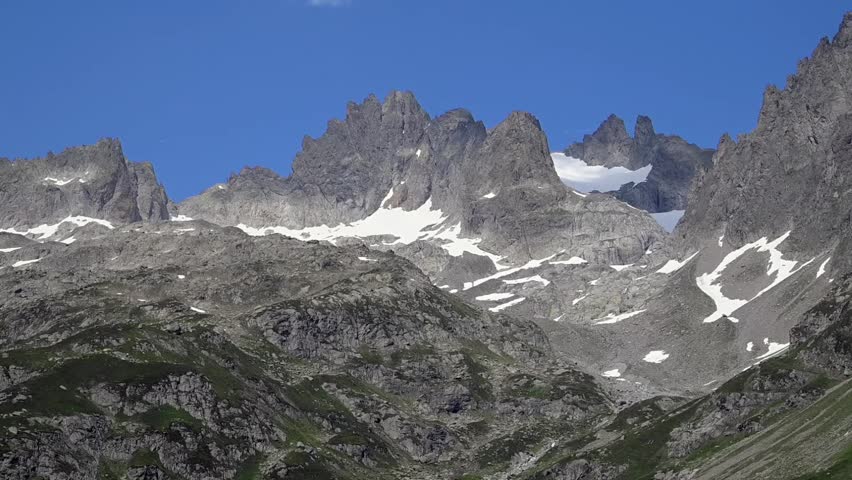 Jagged mountain ridge with lingering snow patches under clear blue sky in the Swiss Alps near Sustenpass.