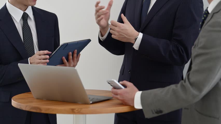 Japanese Businessmen in Their Thirties and Fifties Having a Meeting Using a Laptop and Tablet
