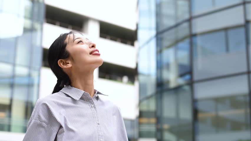 Japanese Businesswoman in Her Thirties Looking Up in an Office District