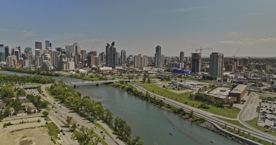 Calgary AB Canada Aerial v1 flyover Westmount across Bow river capturing traffic on Mewata Bridge and riverfront cityscape of Downtown West End on the skyline - Shot with 5k Camera - July 2023