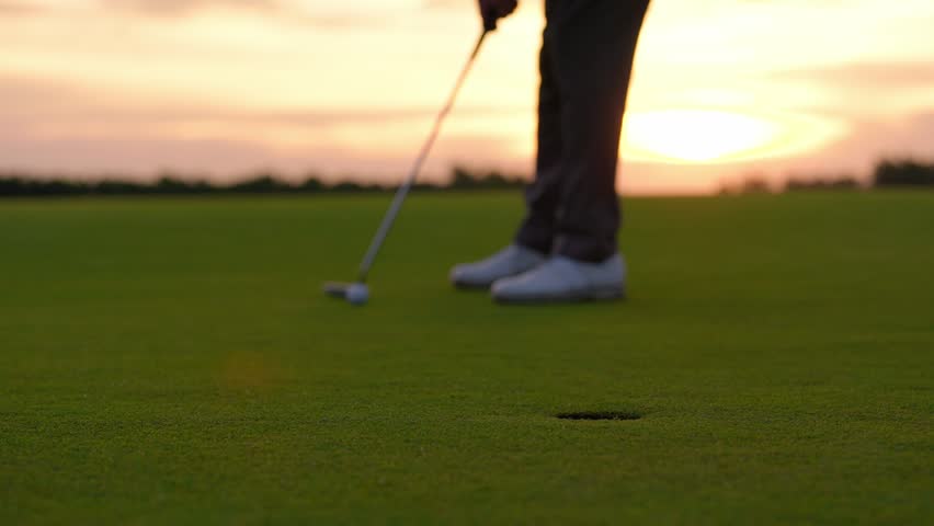 Close up of young male golfer swings his club on scenic golf course. Attractive sportsman enjoying outdoor recreation with light exercise and sport lifestyle while playing golf at course grounds.