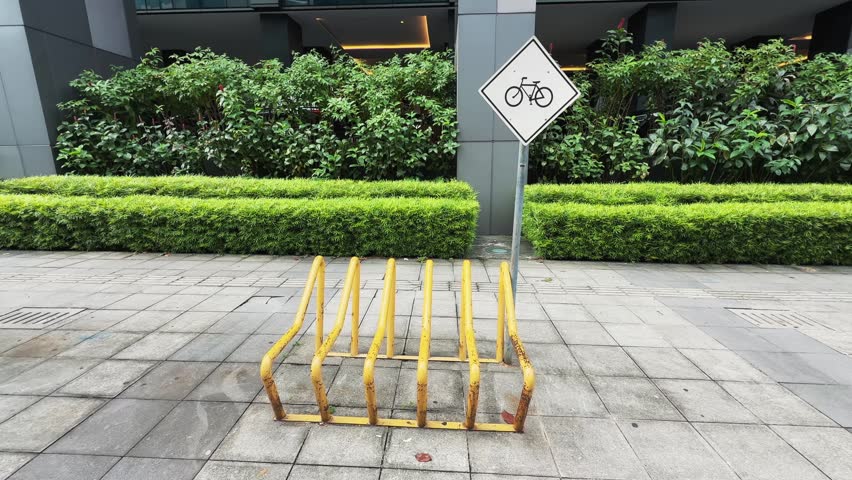 Yellow empty Bicycle Parking Rack with Cycling Sign on Paved City Sidewalk 