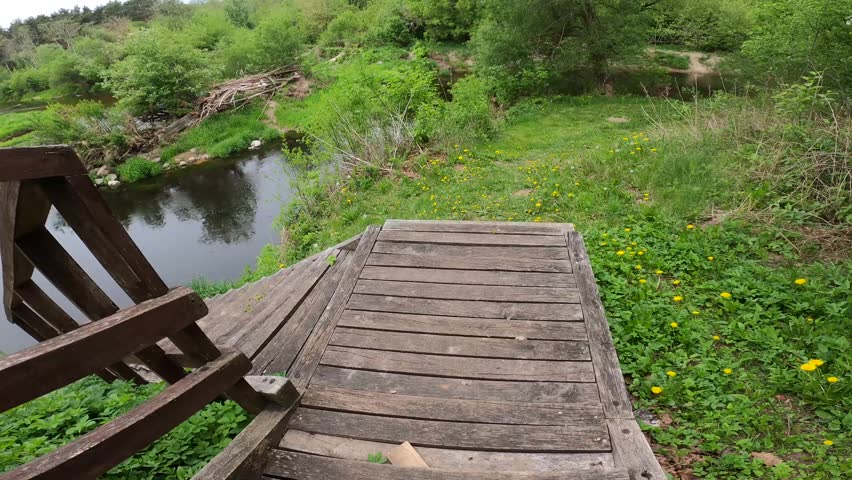 High angle view of a country river looking from old wooden stairs in a green valley