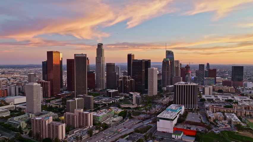 LA skyscrapers in dusk with traffic. Downtown Los Angeles from drone. Sunset over Los Angeles cityscape. Evening sky over Los Angeles traffic. Aerial shot over Los Angeles.