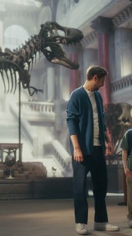 Vertical Screen: Natural History Museum With a Father and Young Son Holding Hands, Watching and Learning About a Giant T-rex Dinosaur Skeleton. Family Vacation Fun and Education
