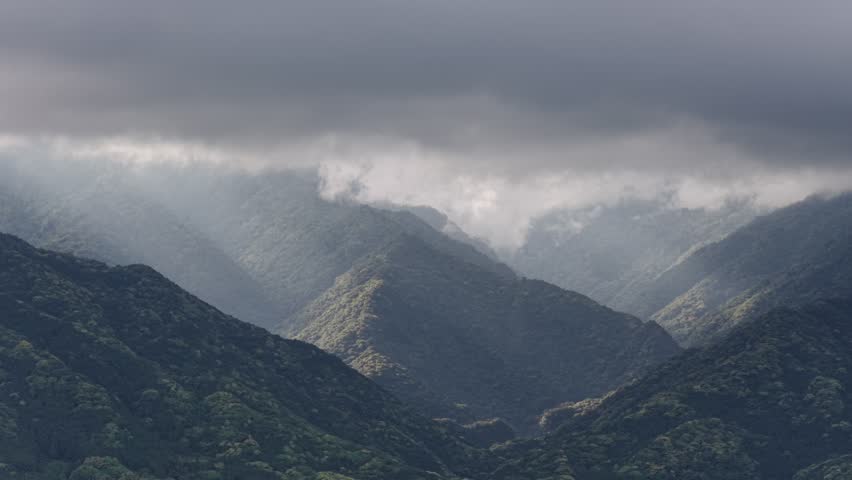 Aerial view of morning light shining through clouds on mountain forest on Yakushima Island
