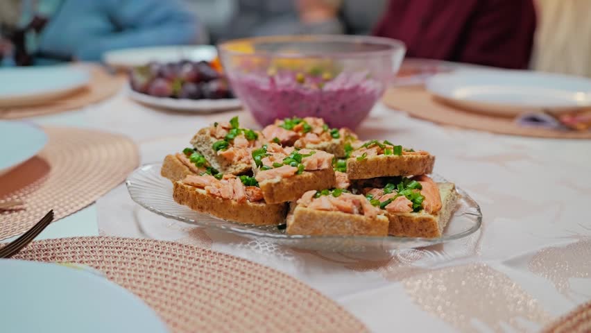 Camera slowly zooms toward smoked salmon sandwiches served on a festive table