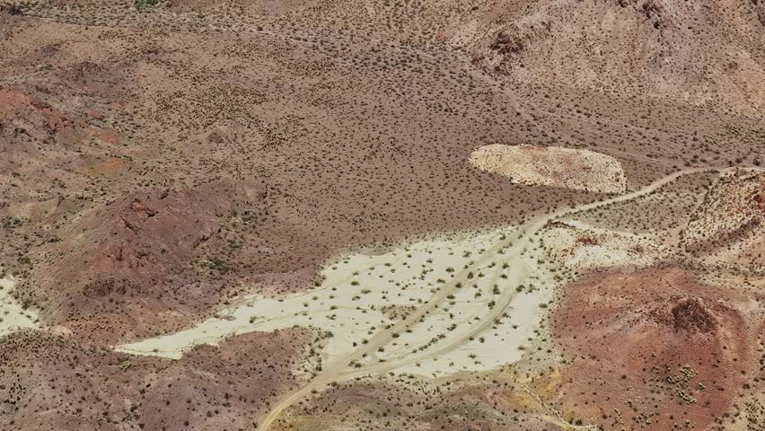 A vast desert area in the USA. There are rocky hills and limited plant life. The ground is mainly dirt with some small shrubs scattered throughout the landscape.