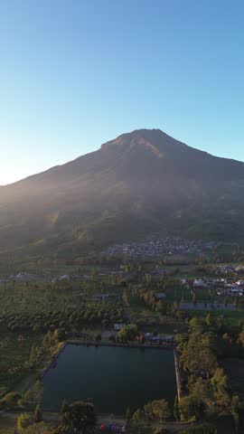 Majestic Volcano Towering Over Village and Pond at Golden Hour