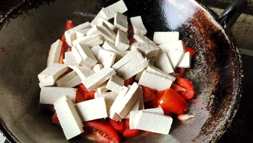 Frying tofu with  tomatoes in pan, indoor Chiangmai Thailand.