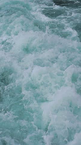Powerful waves surge and crash against rocky shore during daylight.