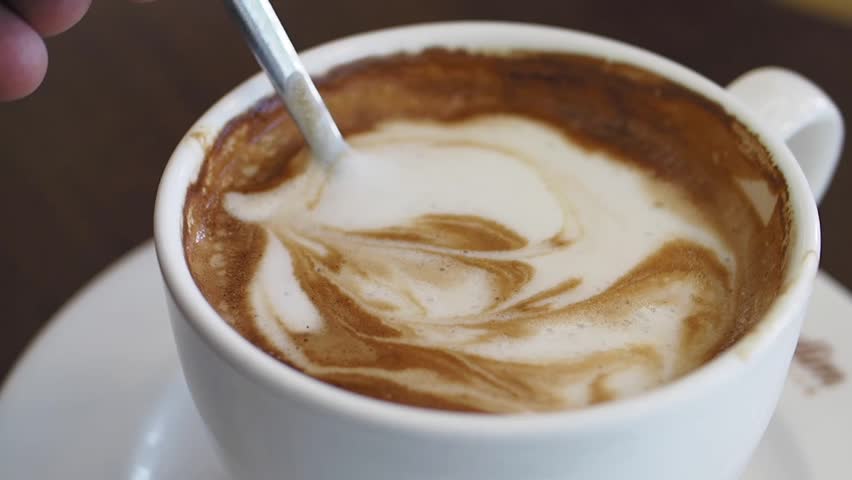 Barista creates beautiful swirling patterns in a cappuccino.