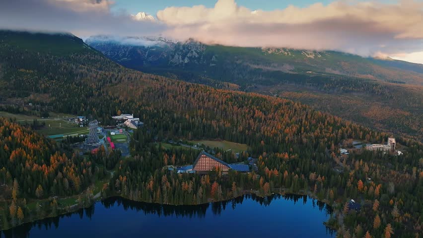 Strbske Lake, Slovakia - 4K Flying above Strbske Lake (Strbske Pleso) on a sunny autumn afternoon with High Tatras Mountains at background. Warm colors, low clouds at the mountains