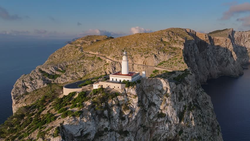 Mallorca, Spain - 4K Flying around of the Lighthouse at Cap de Formentor at sunrise with amazing golden coloured cliffs and colorful clouds at background