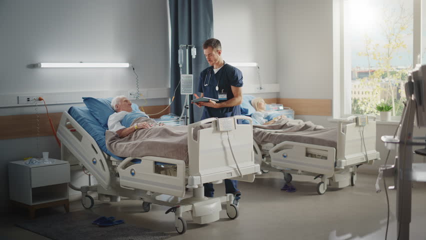 Hospital Ward: Friendly Male Nurse Talks Reassuringly to Elderly Patient Resting in Bed. Doctor or Physician Uses Tablet Computer, Does Checkup, Old Man Fully Recovering after Successful Surgery