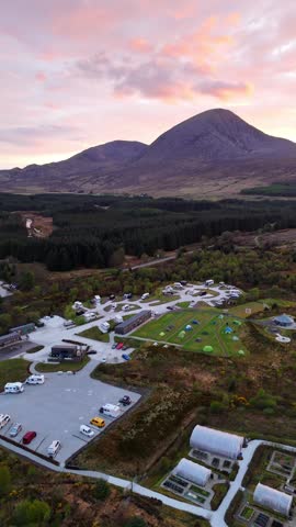 A vertical drone shot overlooking Skye Campsite on the Isle of Skye, Scotland, with a stunning sunset painting the sky in warm hues