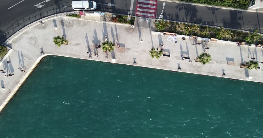 An aerial view of the city of Split, featuring its waterfront in the waters of the Adriatic, with people walking and cars on a sunny summer day, evoking a sense of Tranquility, Split, Croatia