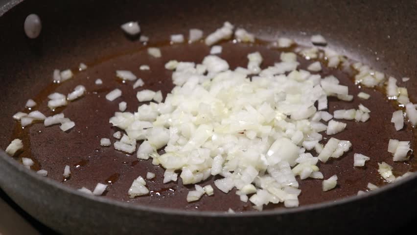 Sautéing Finely Chopped Onions in Hot Oil in a Skillet Close Up