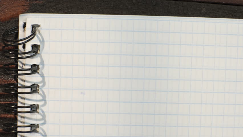 Man writes letter on sheet of notebook paper with fountain pen while sitting at desk close-up, pov view