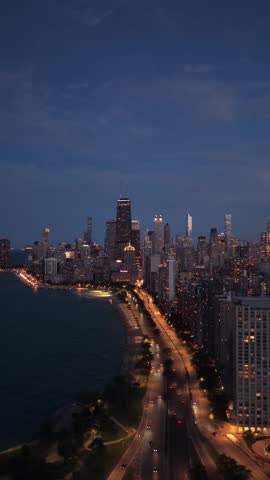 Scenic Chicago skyline glowing at night with Lake Shore Drive traffic and illuminated John Hancock Center overlooking Lake Michigan waterfront and urban metropolis