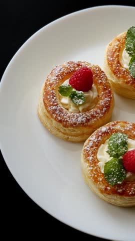 Raspberry puff pastry tartlets with cream and mint on plate, powdered sugar dessert