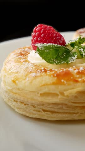 Raspberry cream tartlet rotating on plate, puff pastry dessert close-up.