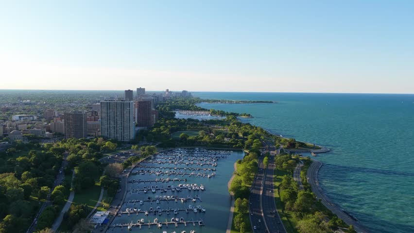 Scenic aerial of Belmont Harbor and Lincoln Park alongside Lake Michigan shoreline with Lake Shore Drive traffic and Chicago