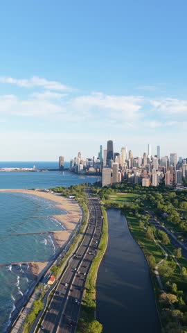 Chicago skyline revealing its towering skyscrapers along Lake Michigan with cars driving on Shore Drive, revealing beach and magnificent city in vertical