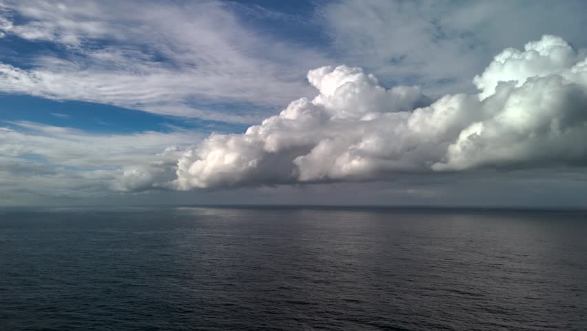 Spectacular storm clouds forming over ocean from aerial view. Camera pans from left to right