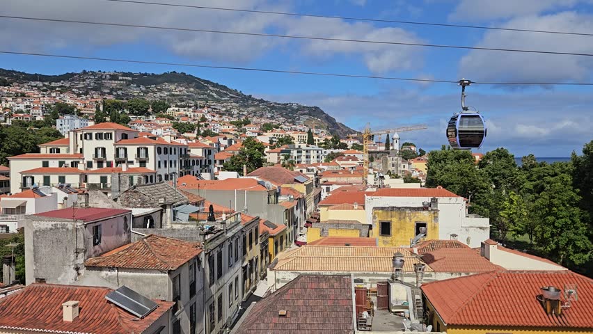 Funchal Cable Car cabin suspended over historic Old Town rooftops with the Atlantic Ocean, Madeira, Portugal
