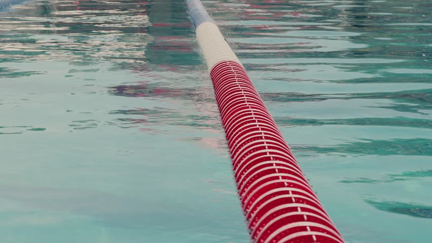 Still shot of a floating lap lane divider with gentle ripples on calm pool water.