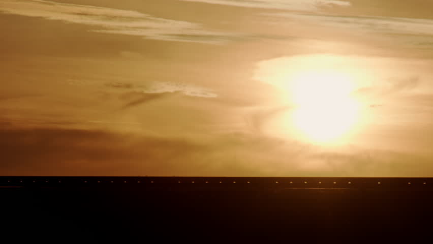 Silhouette of truck with semi-trailers driving on road against background of picturesque sunset sky with clouds in evening twilight
