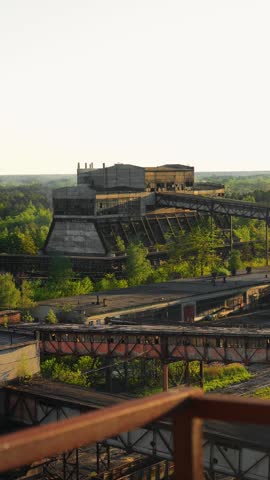 The coal plant workshop is smoking. Gallery with a conveyor belt of an old abandoned coal plant. Sunset, golden hour. Post-apocalyptic atmosphere. Coal enrichment and processing factory