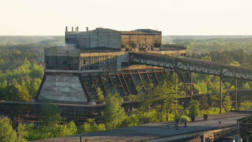 The coal plant workshop is smoking. Gallery with a conveyor belt of an old abandoned coal plant. Sunset, golden hour. Post-apocalyptic atmosphere. Coal enrichment and processing factory