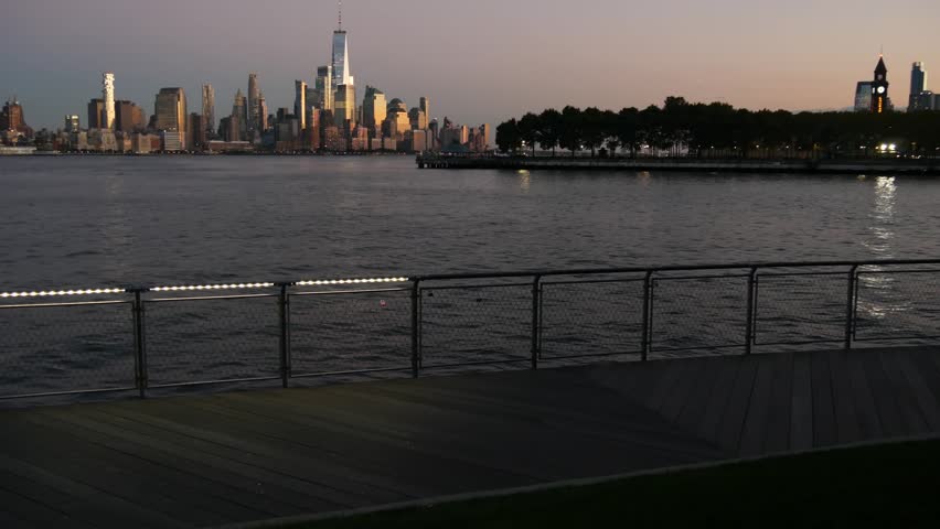 New York City Manhattan Downtown Financial District skyline, World Trade Center tower skyscraper from New Jersey, Hoboken pier, United States. River waterfront urban cityscape, evening dusk twilight.