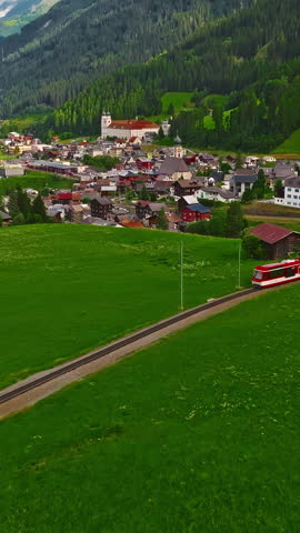 Establishing shot of Switzerland. Aerial view of the green meadows of Switzerland, with the Alps and clouds in the background