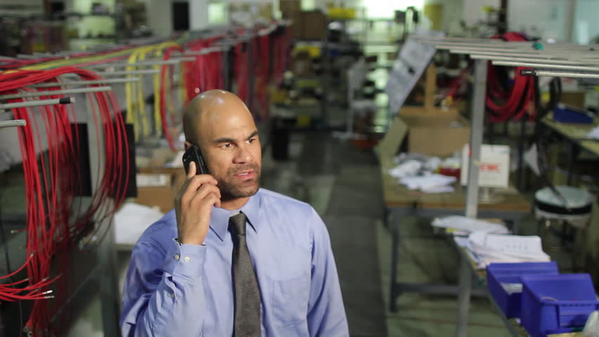 Business man on happy phone call in industrial setting.