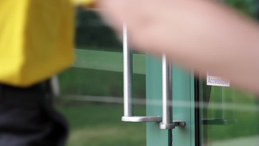 Detail view of hand opening a door with accessible access sticker.