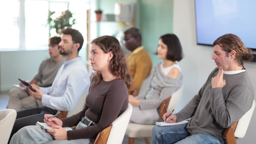 Multinational group of men and women listens to lecture and takes notes in lecture hall