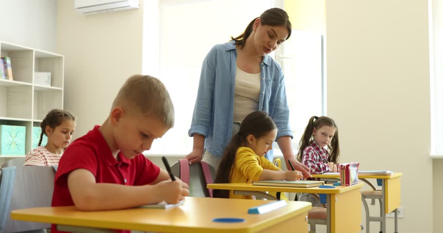 Teacher helping student during lesson in classroom