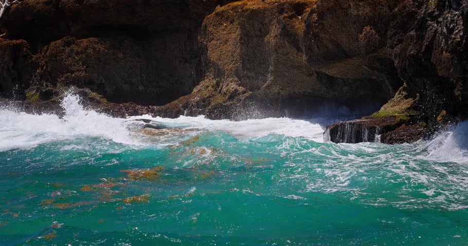 Turquoise ocean waves crashing against rocky coastline with sea foam