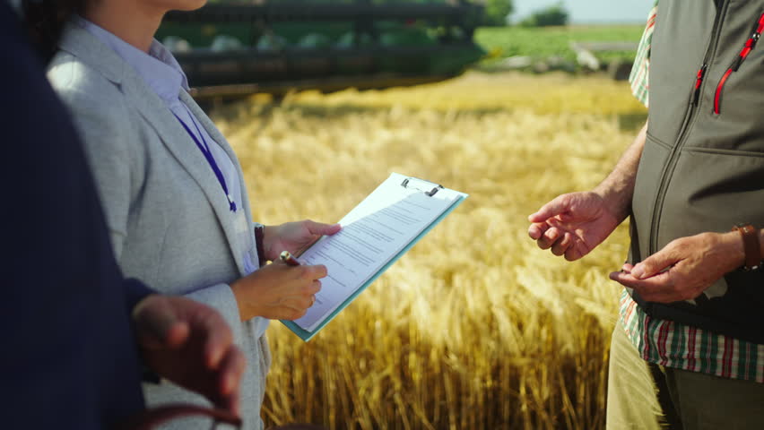Close-up of a farmer signing documents in a wheat field, representing farm financing, agricultural contracts, subsidies, investment and rural business agreements.
