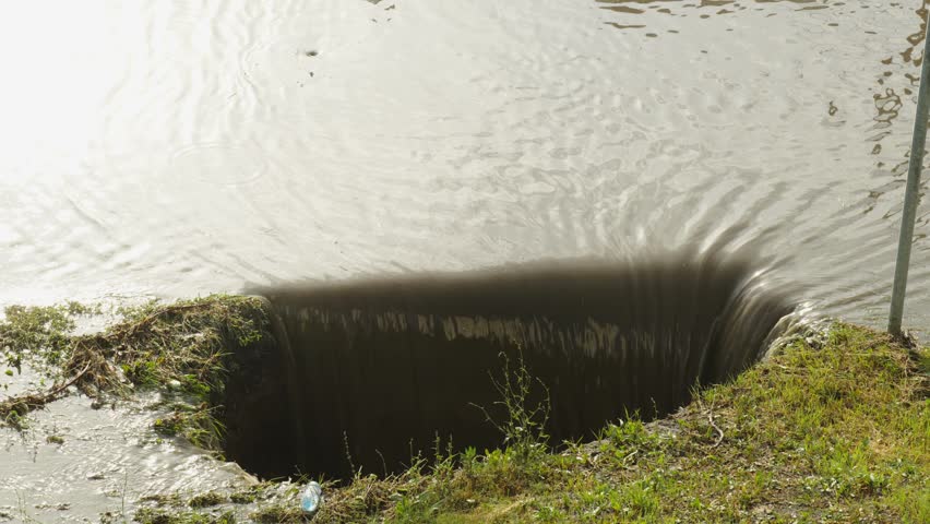 Water flows into a large concrete spillway hole at lake.