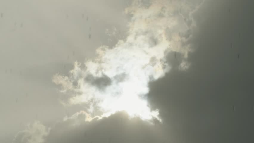 Bright sun peeking from behind a large dark storm cloud